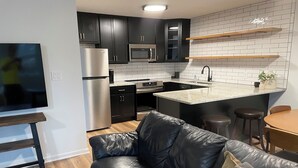 Una cocina moderna con armarios oscuros, electrodomésticos de acero inoxidable y una isla central.