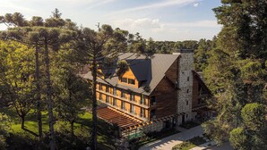 Una grande casa a più piani in legno, circondata da alberi, con un camino in pietra e un'area esterna coperta.