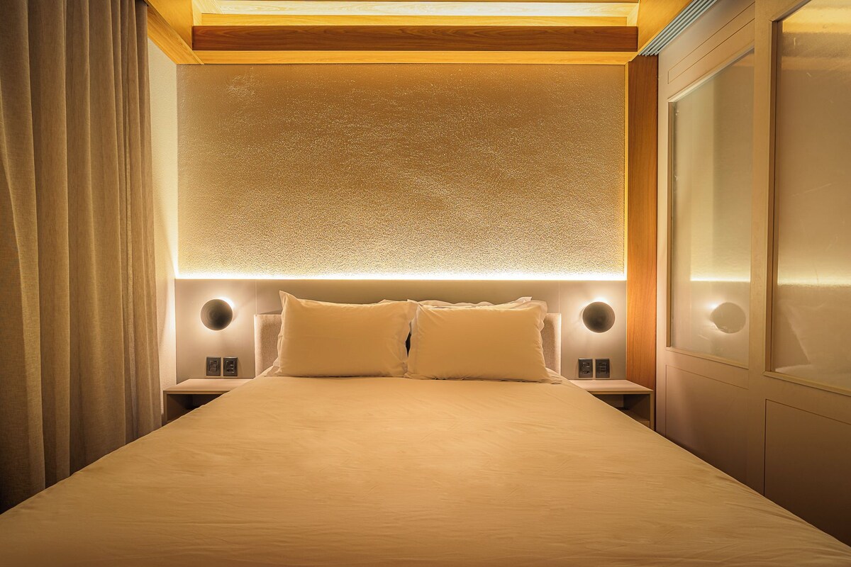 Een hotelkamer met een groot bed, twee nachtkastjes en een wandlamp.