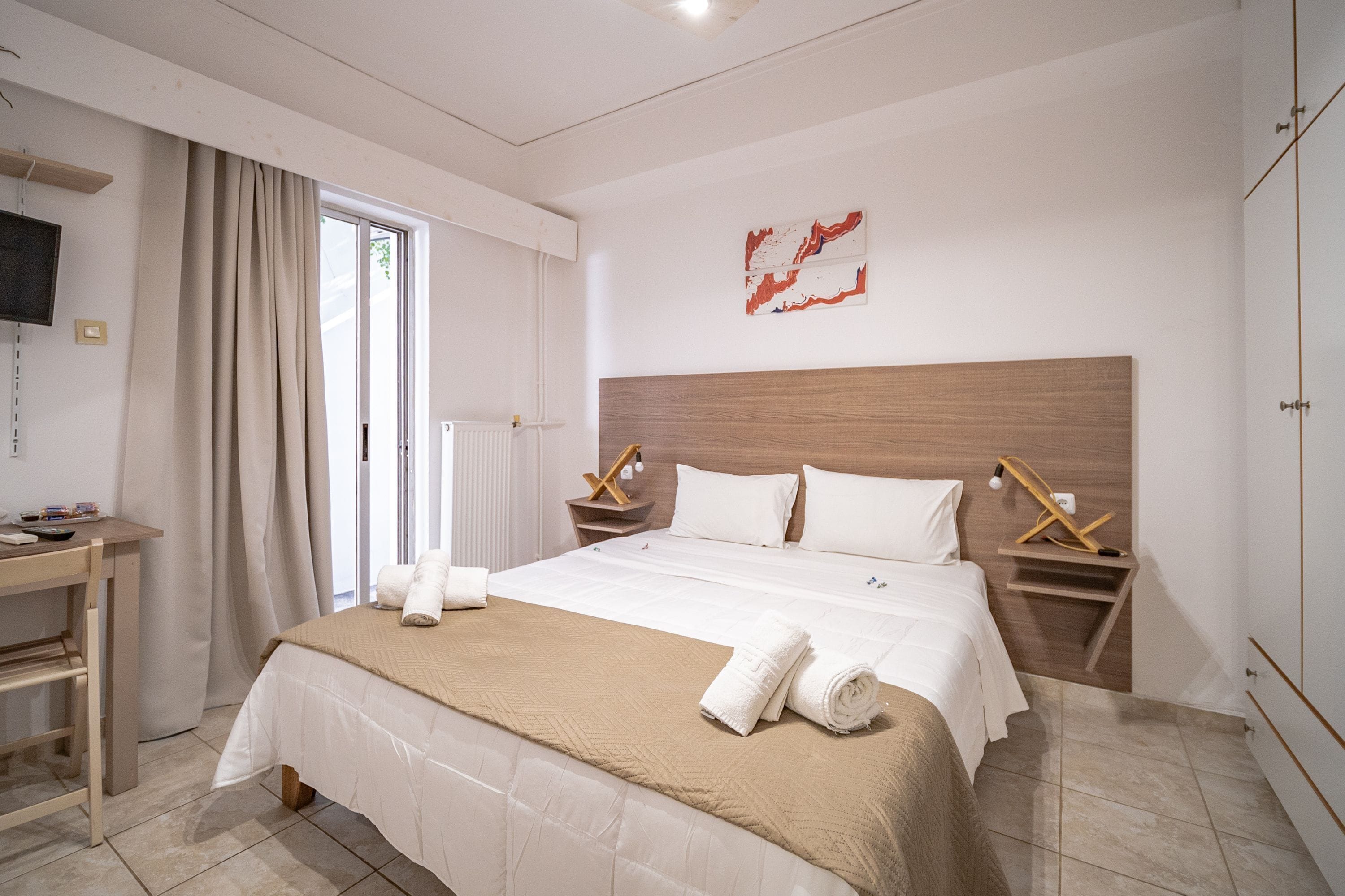 Habitación de hotel con una cama grande, un escritorio y un televisor en la pared.
