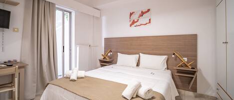 Habitación de hotel con una cama grande, un escritorio y un televisor en la pared.