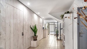 A modern hallway with wooden panel walls, a potted plant, and a tiled floor. - City Center Studios by Cretan Houses (Heraklion)