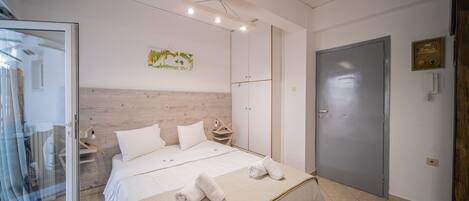 Une chambre à coucher moderne avec un grand lit, une tête de lit en bois, une table de chevet et une armoire.