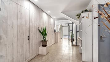 Un pasillo moderno con paneles de madera, una planta en maceta y suelo de baldosas.