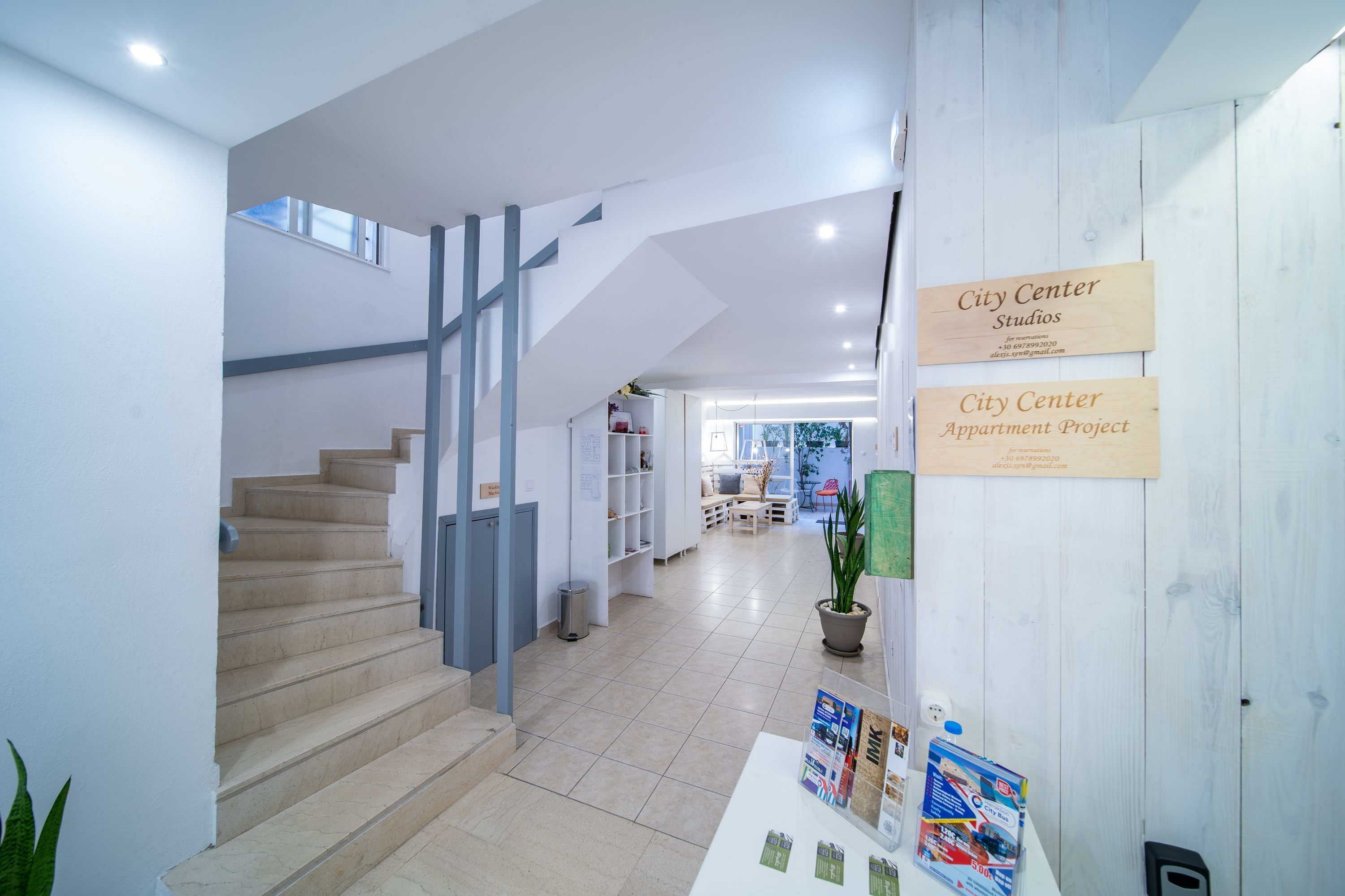 A modern interior with a staircase, a reception desk, and informational signs.