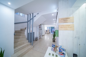 A modern interior with a staircase, a reception desk, and a sign indicating the City Center Studios and Apartment Project. - City Center Studios by Cretan Houses (Heraklion)