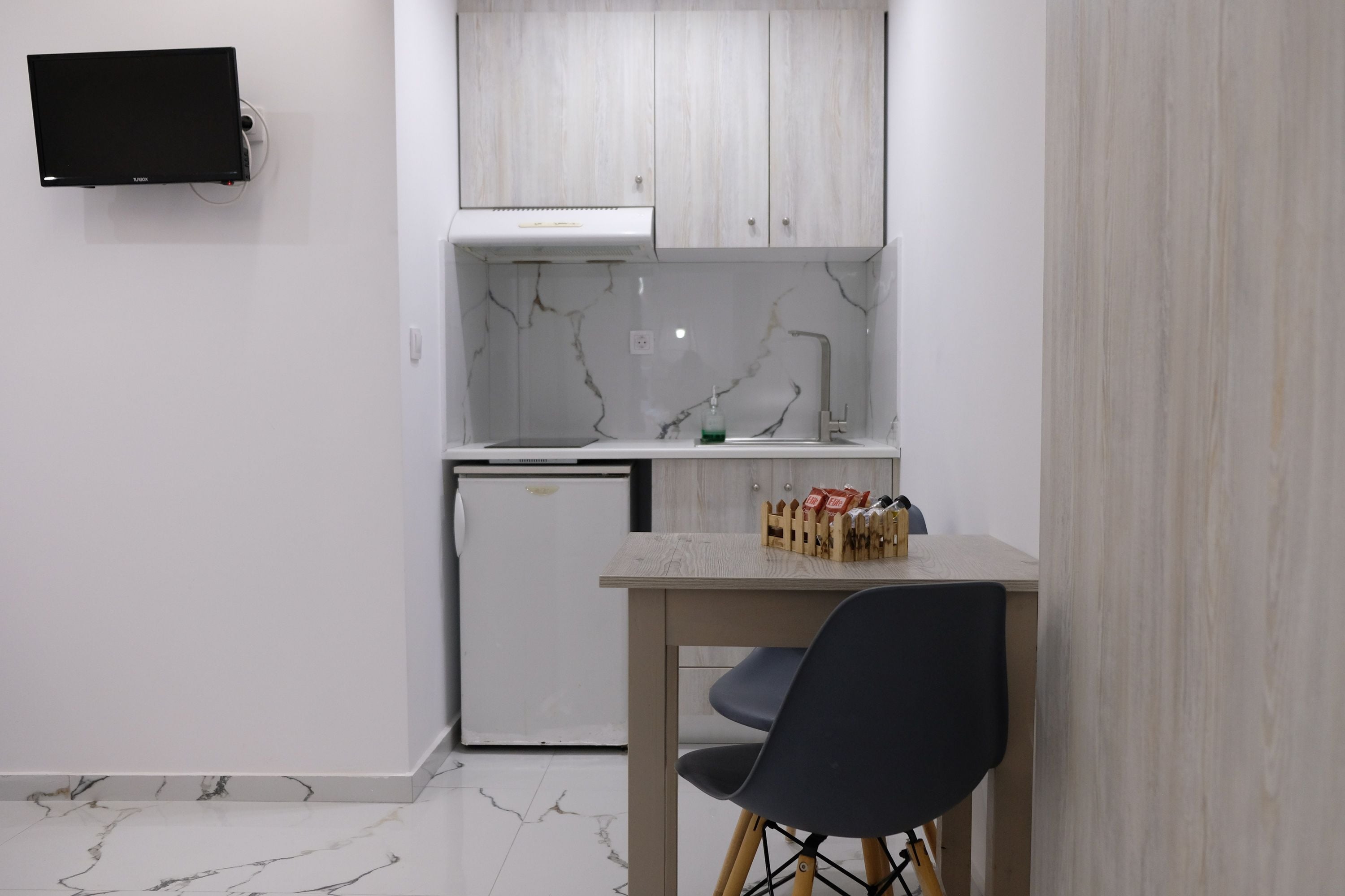 A compact kitchen with white cabinets, a built-in microwave, and a small refrigerator.