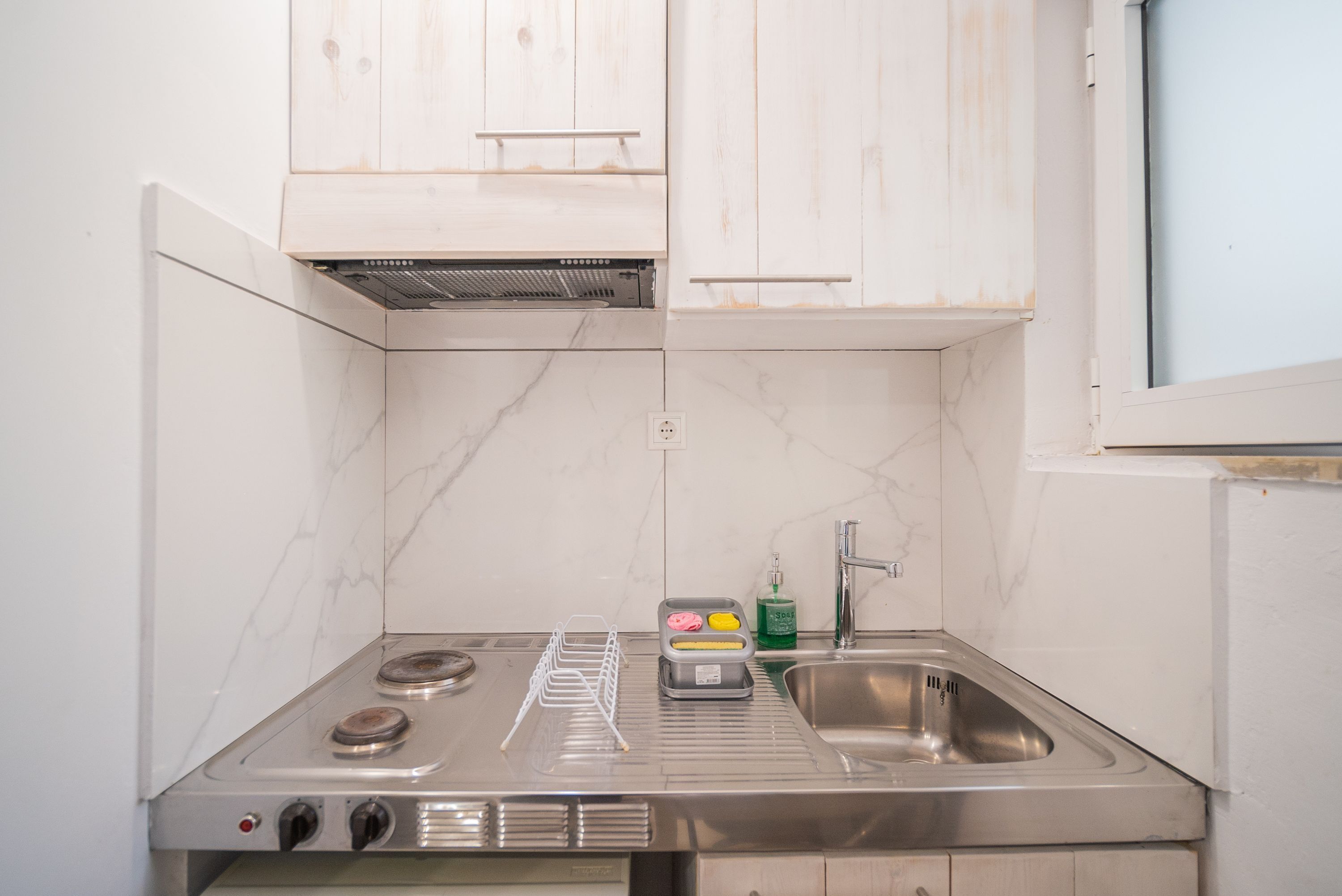 A compact kitchen with a stainless steel stove, a sink, and white cabinets.