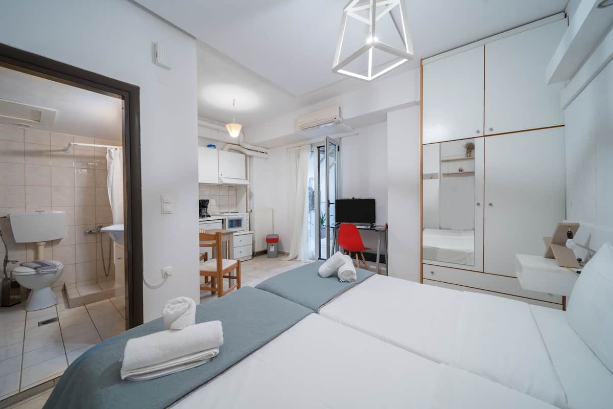 A hotel room with a bed, a desk, a chair, a wardrobe, and a bathroom.