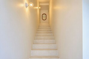 Eine Treppe mit einer Wandleuchte und einem Spiegel oben.