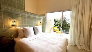A bedroom with a large bed, a view of greenery outside, and a sliding glass door. - Brand New Town House (Puntarenas)