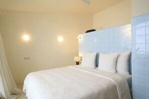 A hotel room with a bed, a nightstand, and a wall-mounted light fixture.