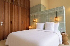 Habitación de hotel con una cama grande, paneles de madera en una pared y una pared con baldosas y lámparas colgantes.
