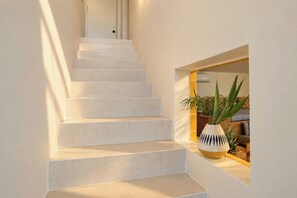 Una escalera de diseño moderno que lleva a una habitación con una planta y un sofá.