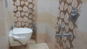 Een badkamer met toilet, douche en een muur met bladpatroon.