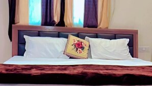 Een bed met een houten hoofdbord, witte beddengoed en één decoratief kussen.