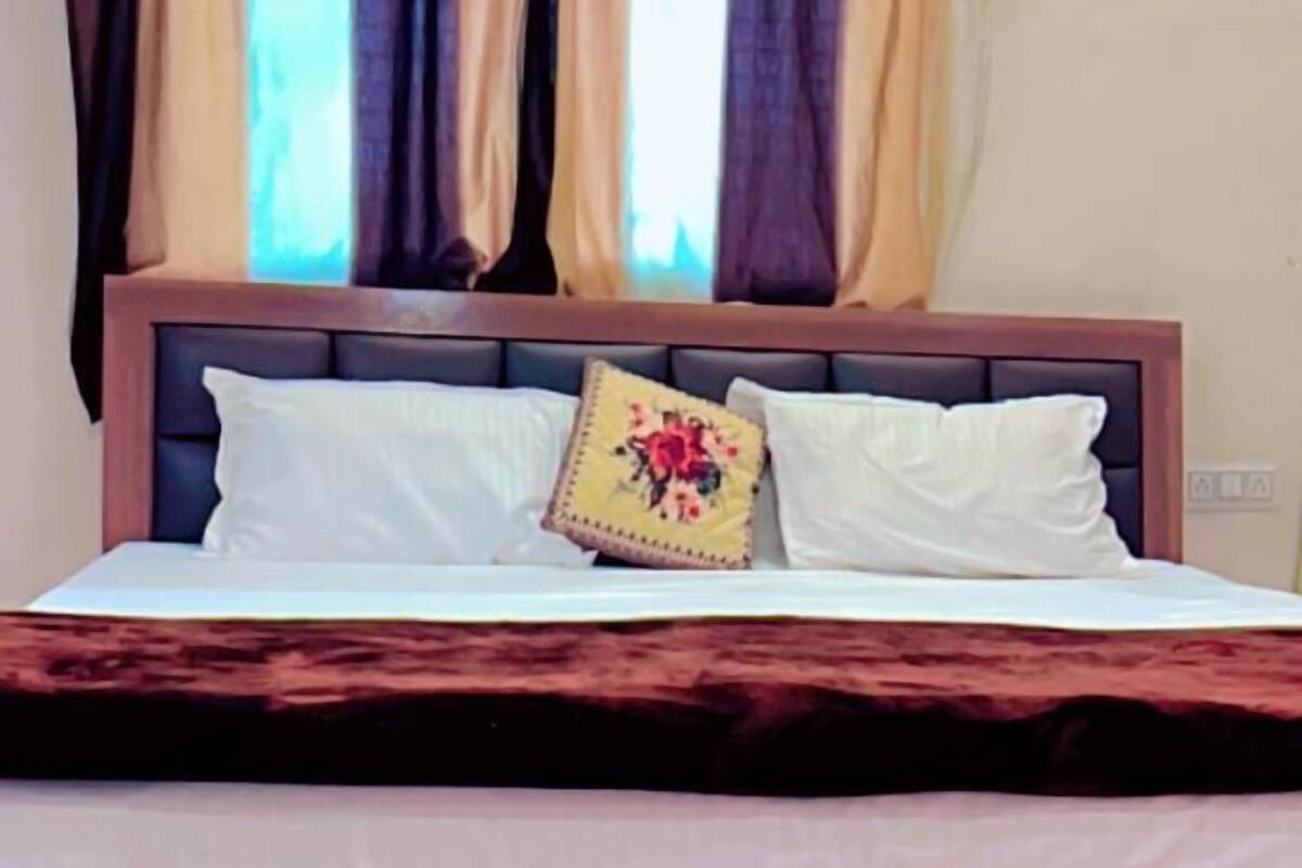 Ein Bett mit Holz Kopfteil, weißer Bettwäsche und einem einzelnen Zierkissen.