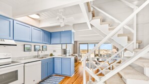 Una cocina moderna con armarios azules, electrodomésticos blancos y suelo de madera.