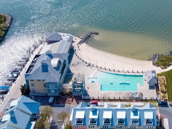 Vista aérea de un hotel costero con piscina, acceso a la playa y zona de estacionamiento.
