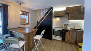 Una cocina compacta con una barra de madera, sillas blancas, un horno y un fregadero.