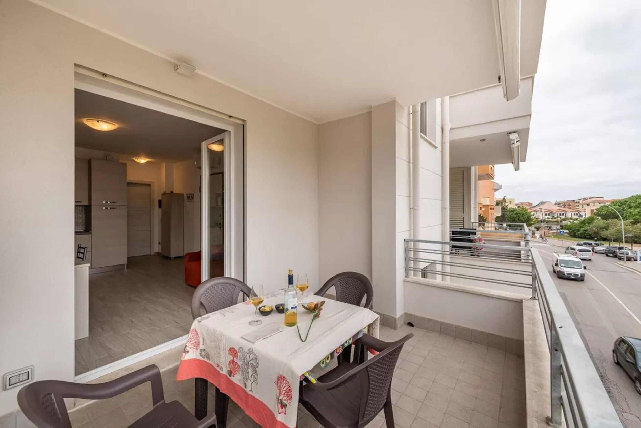 A balcony with a table set for two, chairs, and a view of the street.