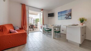 Una sala de estar moderna con sofá, mesa de comedor, sillas y una pequeña cocina.