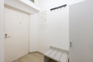 A small, enclosed room with a door, a small window, and a shelf with a light fixture above it.