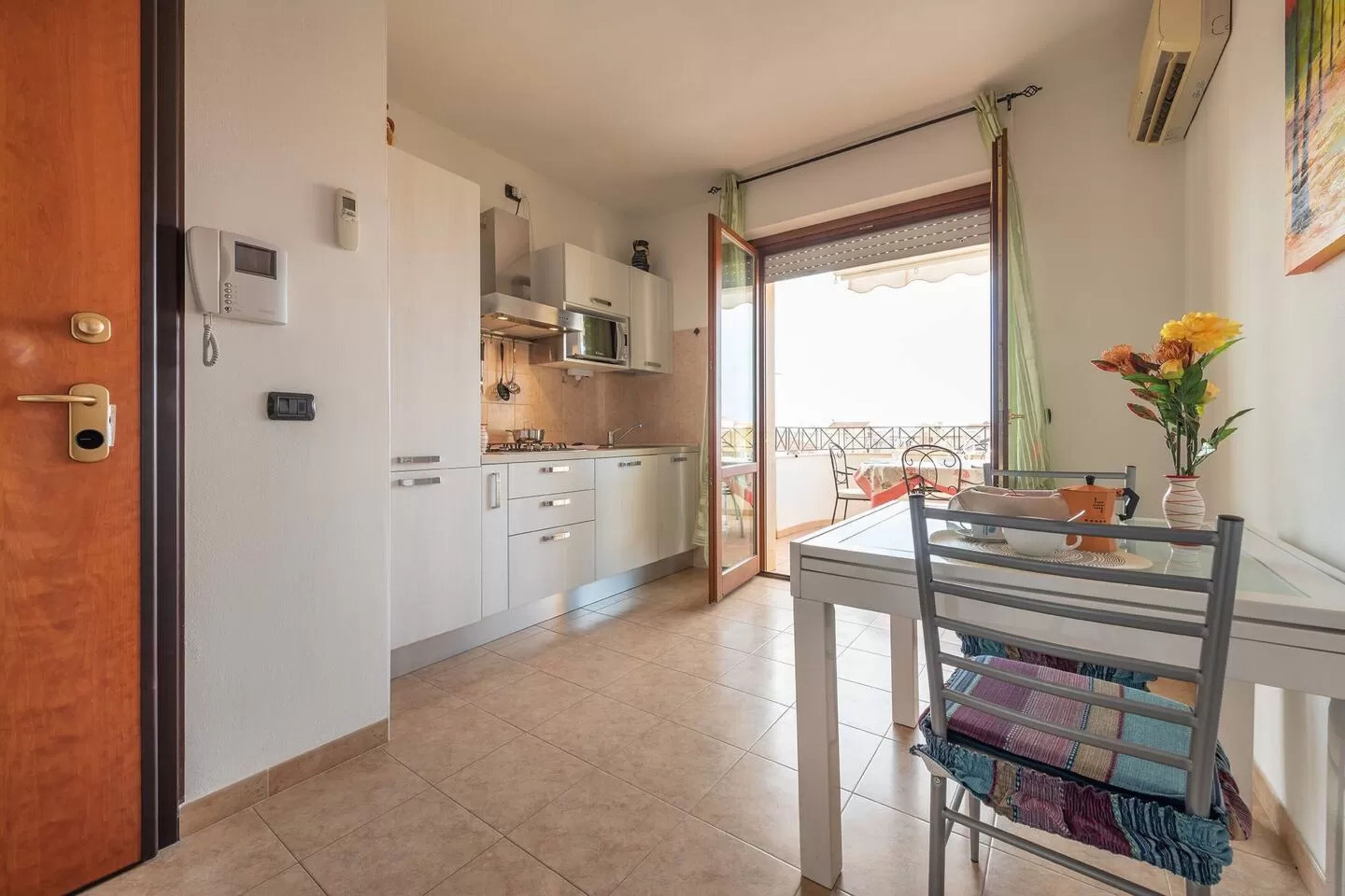 A modern kitchen with white cabinets, a microwave, and a dining area with a table and chairs.