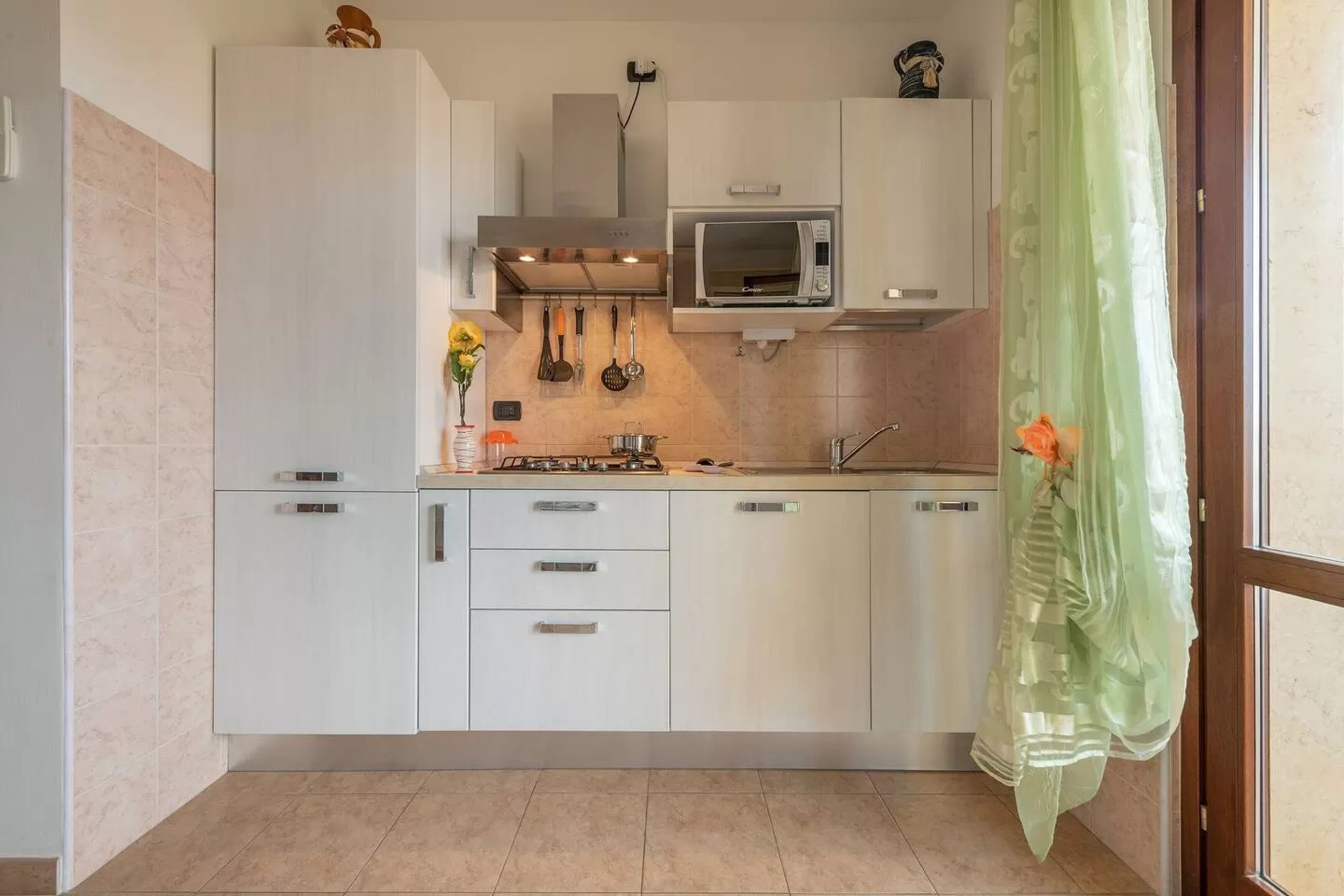 Une cuisine moderne avec des meubles blancs, un four à micro-ondes et une cuisinière à gaz.