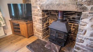 Una chimenea de piedra con un televisor sobre un soporte de madera a su lado.