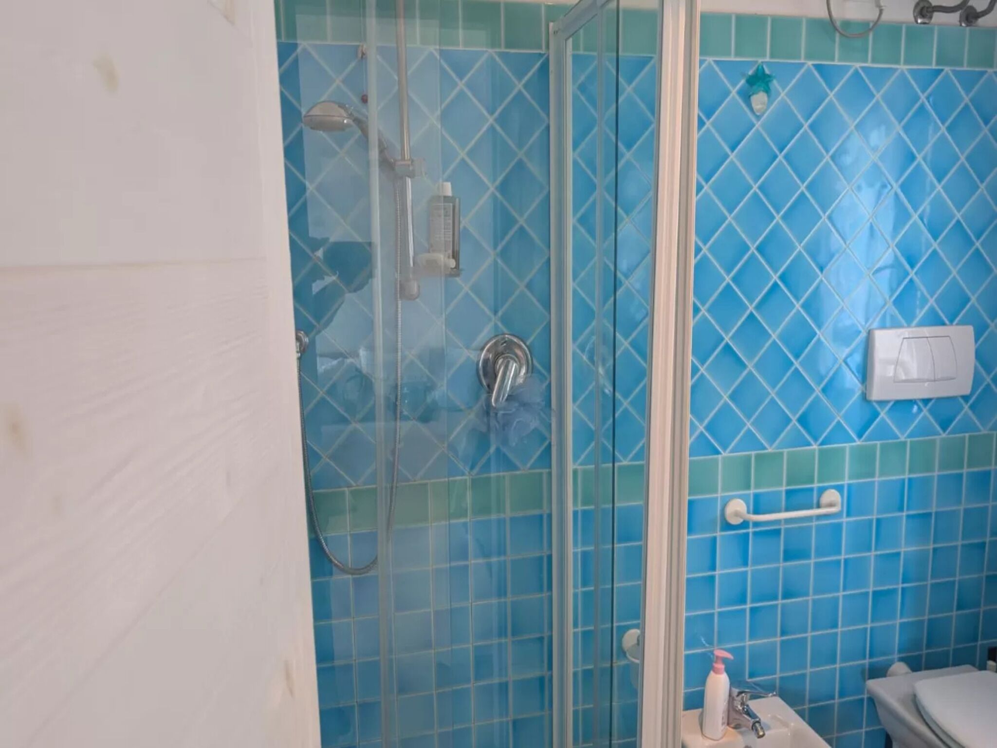 A bathroom with a glass-enclosed shower, a toilet, and a sink.