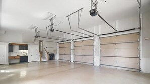 Un garaje espacioso con piso de concreto, una escalera y una zona de cocina con armarios y mostrador.