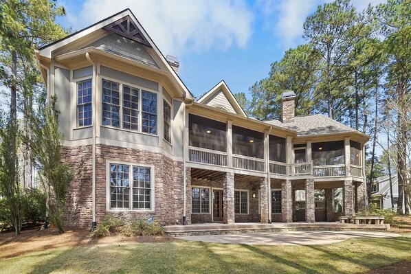 A large, two-story house with a stone facade, multiple windows, and a covered porch area.