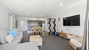 A modern living room with a sofa, coffee table, and a TV mounted on the wall.