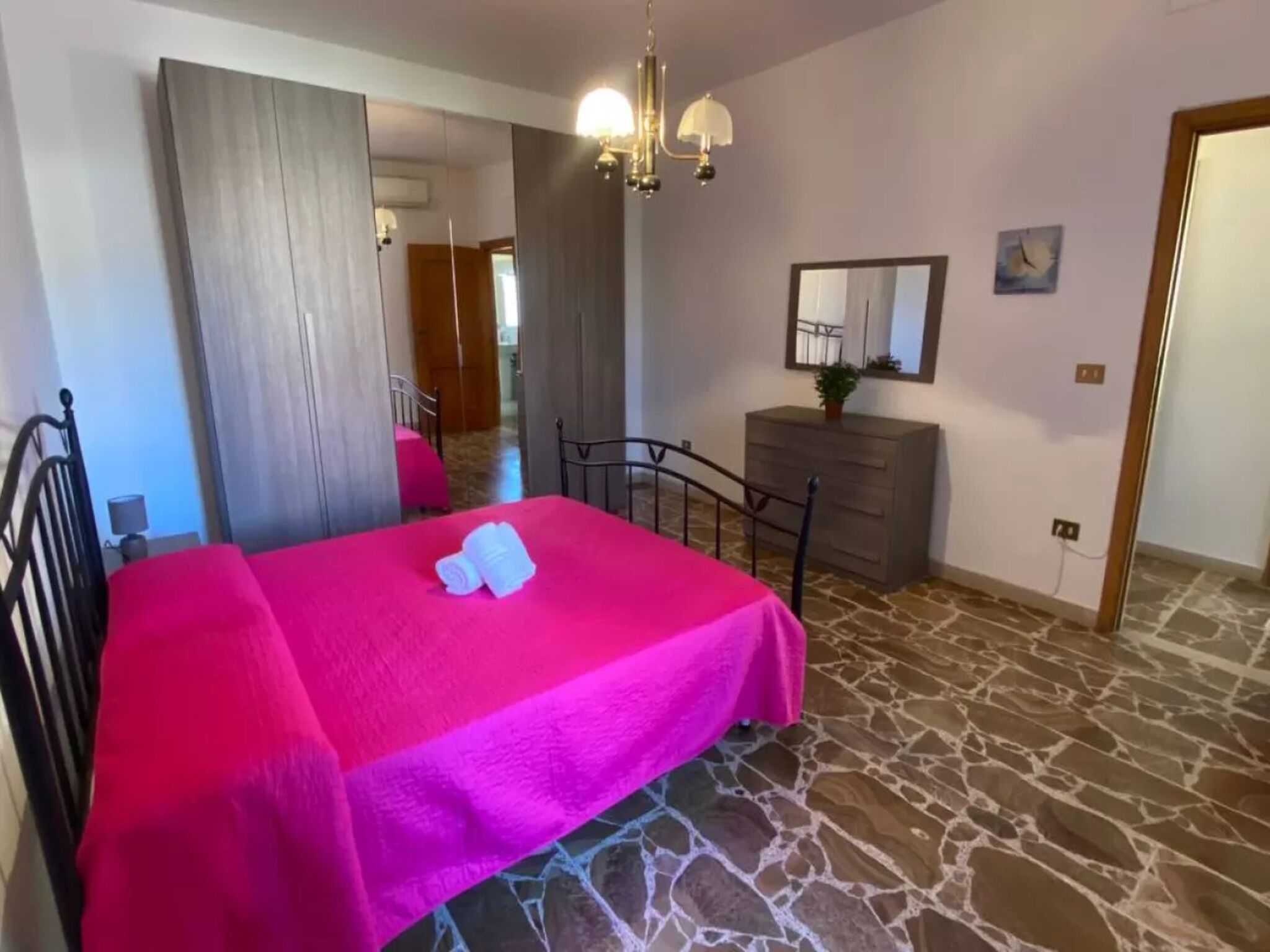 Een slaapkamer met een bed, een kaptafel, een spiegel en een kroonluchter.
