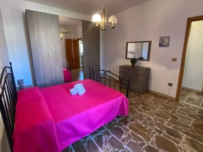 Une chambre à coucher avec un lit, une commode, un miroir et un lustre.