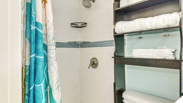 A shower with a showerhead, a towel rack, and a toilet.