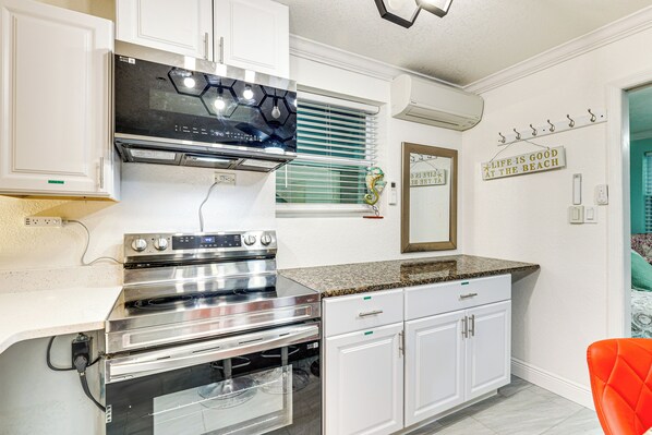 A modern kitchen with stainless steel appliances, white cabinetry, and a granite countertop.