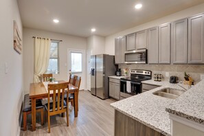 A modern kitchen with a dining area, stainless steel appliances, granite countertops, and light wood cabinetry. - 6 Mi to Lackland Afb: Hot Tub, Pool & Game Room! (San Antonio)