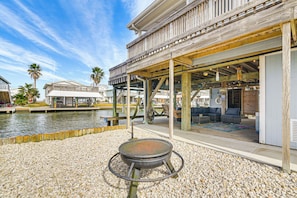 A waterfront property with a covered outdoor seating area, a fire pit, and a view of the water.