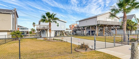 Um bairro residencial com casas, um quintal cercado e céu limpo.