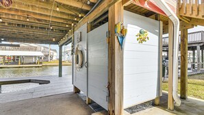 A covered wooden structure with a lifebuoy mounted on the wall, a wooden deck, and a view of a water body. - Fish, Crab, Unwind! Canal-front Gem in Galveston (Galveston)