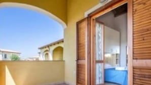Un balcon avec une porte en bois donnant sur une pièce comprenant un lit et un mur bleu.
