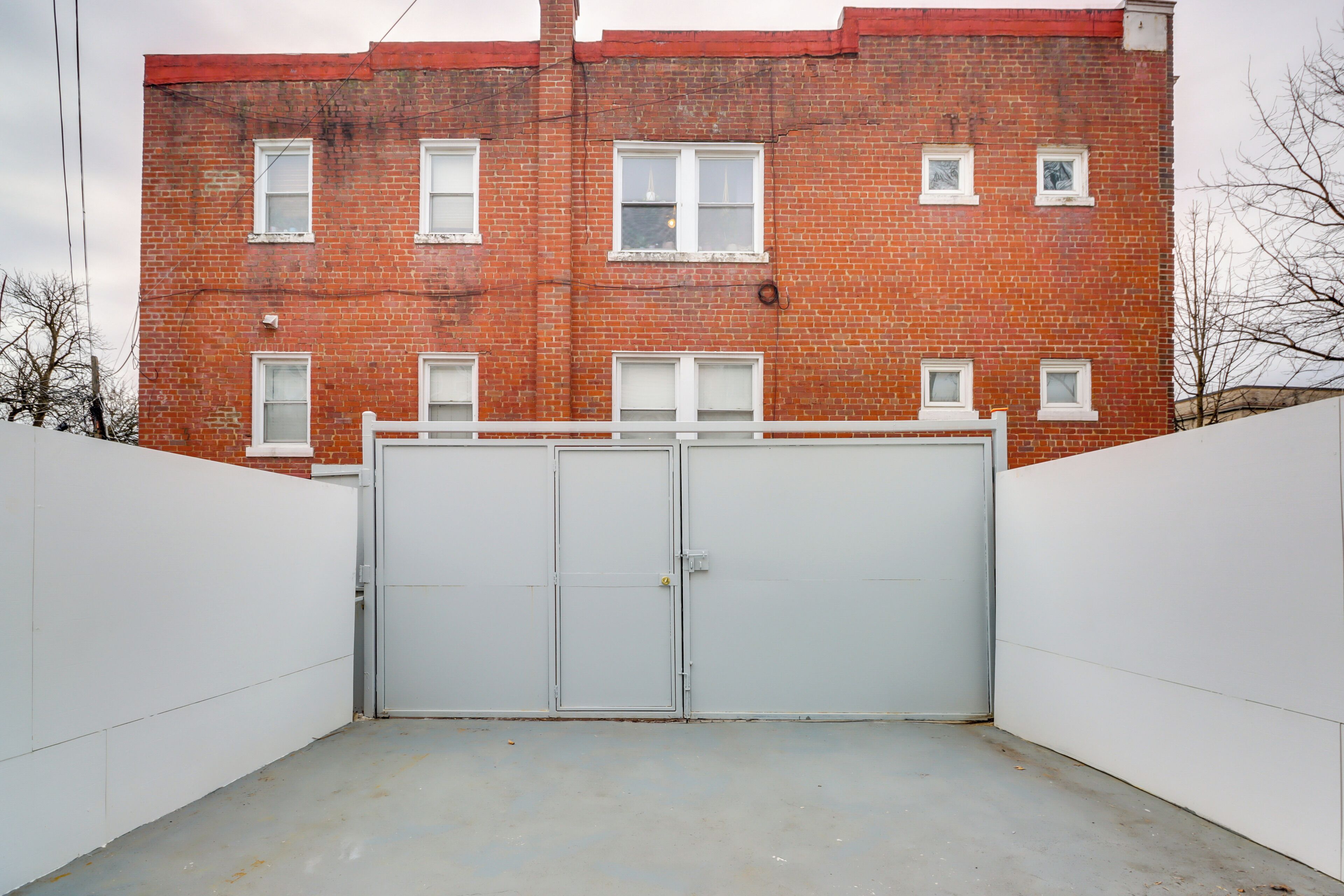A brick building with multiple windows and a gated entrance.