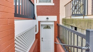 A narrow, red brick alleyway with a white door and a small window above it. - 2 Mi to Dtwn DC: Wfh-friendly Apt (Washington)