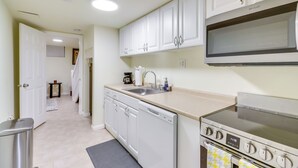 A compact kitchen with white cabinets, a built-in microwave, a dishwasher, and a stove. - 2 Mi to Dtwn DC: Wfh-friendly Apt (Washington)