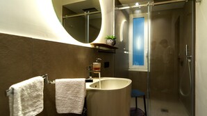A modern bathroom with a large sink, a mirror, and a glass-enclosed shower. - Luxury Ischia in Naples station train (Napoli)