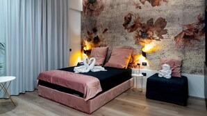 A bedroom with a bed, pillows, a bedside table, and a wall with floral wallpaper. - Luxury Ischia in Naples station train (Napoli)