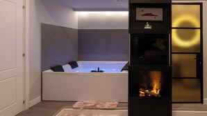 A modern bathroom with a freestanding bathtub, a built-in fireplace, and a framed picture above the fireplace. - Luxury Ischia in Naples station train (Napoli)