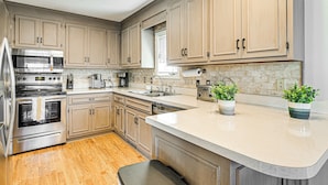 A modern kitchen with stainless steel appliances, wooden cabinets, a large island, and two potted plants. - 1 Mi to Broadway at the Beach: Home w/ Large Yard! (Myrtle Beach)